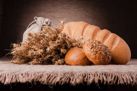 Bread, flour sack and ears bunch still life on rustic backgroundの写真素材
