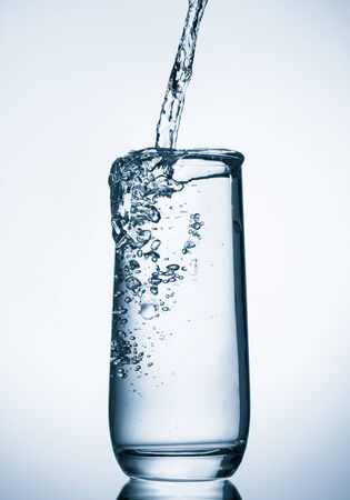 water pouring into glass on blue backgroundの写真素材