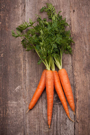 fresh carrot bunch on grungy wooden backgroundの写真素材
