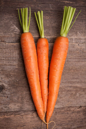 fresh carrot bunch on grungy wooden backgroundの写真素材