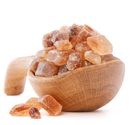 Brown cane caramelized lump sugar in wooden bowl isolated on white background cutoutの写真素材