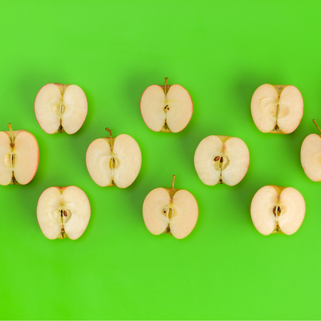 Fruit pattern of apple halves on green background. Flat lay, top view. Food background.の写真素材