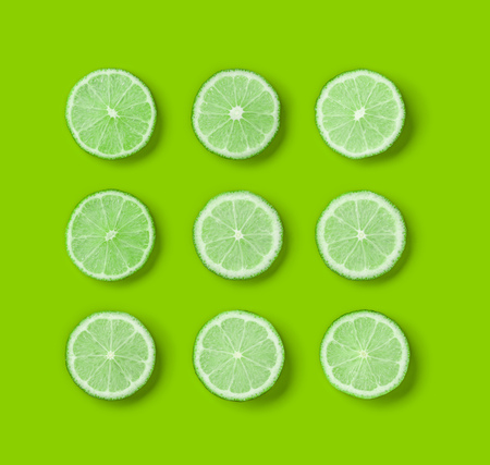 Fruit pattern of lime slices on green background. Flat lay, top view.