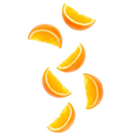 falling fresh orange fruit slices isolated on white background closeup. Flying food concept. Top...