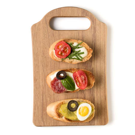Open faced sandwich canape or crostini on a wooden serving board isolated on white background closeup. Top view.の写真素材
