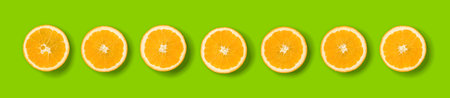Fruit pattern of orange slices on green background. Flat lay, top view. Banner, seamless pattern, creative summer food concept.の写真素材
