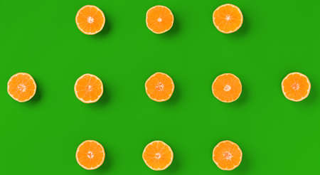 Fruit pattern of fresh orange tangerine or mandarin on green background. Flat lay, top view. Pop art design, creative summer concept. Citrus in minimal style.の写真素材