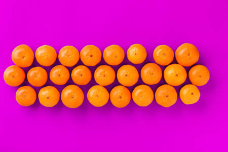 Fruit pattern of fresh orange tangerine or mandarin on lilac background. Flat lay, top view. Pop art design, creative summer concept. Citrus in minimal style.の写真素材