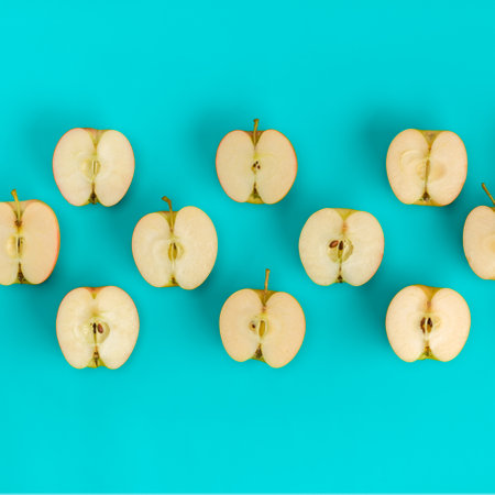 Fruit pattern on blue background. Apple halves geometrical layout. Flat lay, top view. Food background..  Pop art design, creative summer concept.の写真素材