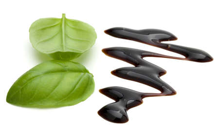 Balsamic vinegar cream and basil leaves isolated on white background. Italian salad dressing, sauce.の写真素材