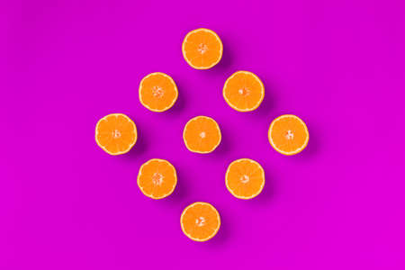 Fruit pattern of fresh orange tangerine or mandarin on lilac background. Flat lay, top view. Pop art design, creative summer concept. Citrus in minimal style.の写真素材