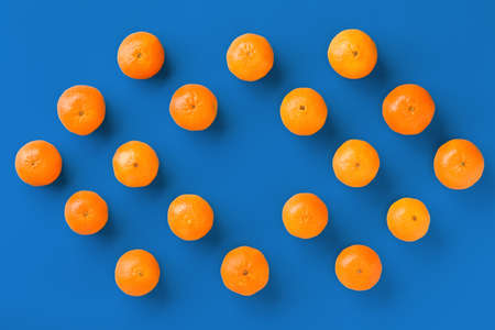 Fruit pattern of fresh orange tangerine or mandarin on blue background. Flat lay, top view. Pop art design, creative summer concept. Citrus in minimal style.の写真素材