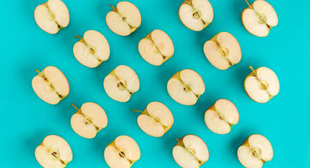Fruit pattern on blue background. Apple halves geometrical layout. Flat lay, top view. Food background..  Pop art design, creative summer concept.の写真素材