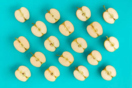 Fruit pattern on blue background. Apple halves geometrical layout. Flat lay, top view. Food background..  Pop art design, creative summer concept.の写真素材