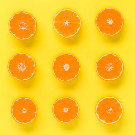 Fruit pattern of fresh mandarin slices on yellow background. Flat lay, top view. Pop art design,...