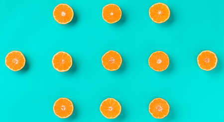 Fruit pattern of fresh mandarin slices over blue background. Flat lay, top view. Pop art design, creative summer concept. Half of citrus in minimal style. Tangerine.の写真素材