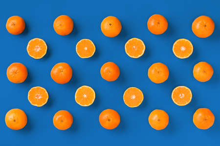 Fruit pattern of fresh orange tangerine or mandarin on blue background. Flat lay, top view. Pop art design, creative summer concept. Citrus in minimal style...の写真素材