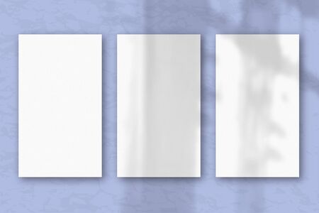 3 vertical sheets of textured white paper on soft blue table background, natural light casts shadows from the window. Horizontal orientation.の写真素材