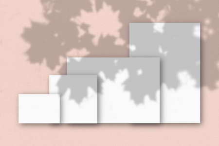 Several horizontal and vertical sheets of white textured paper against a pink wall background....