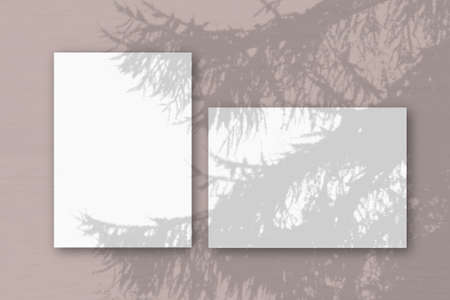 Horizontal and vertical sheets of white textured paper against a pink wall background. Mockup with...