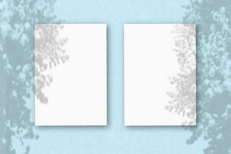 2 vertical sheets of textured white paper on soft blue table background. Mockup overlay with the...