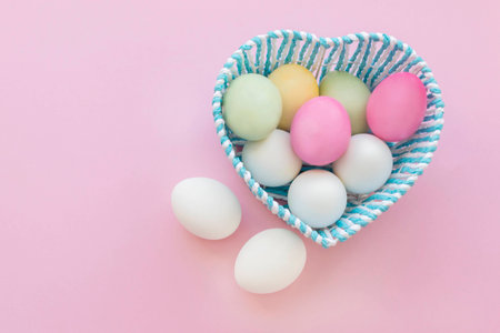 Easter eggs in a blue basket. Painted eggs for the holiday. Pink background.の写真素材