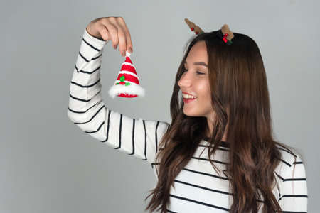 A happy woman holds a Christmas decoration. Grey background.の写真素材