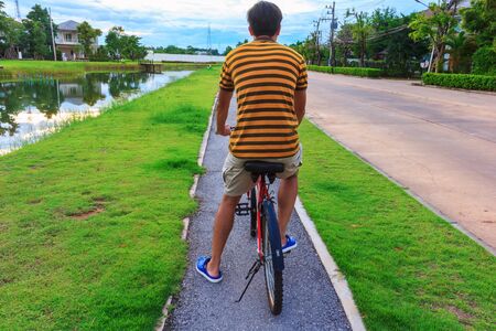 men seat red bike circle on grass in garden village evening timeの写真素材