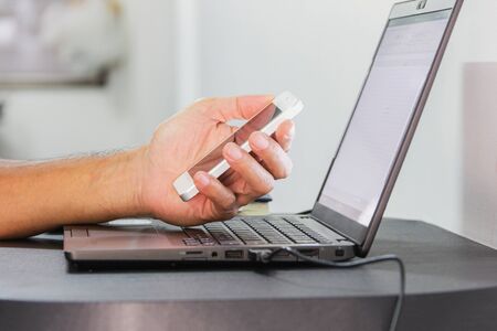 hand hold smartphone near black laptop for work from home