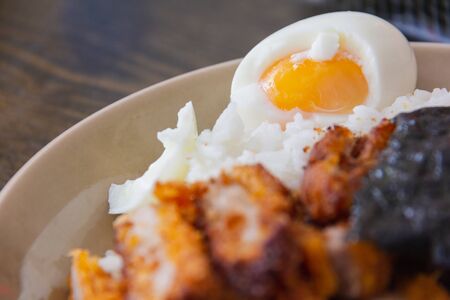 boiled eggs and Pork fried rice with sprinkled with seaweed sheets on a brown plate placed on a wooden tableの写真素材