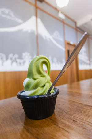 Green tea ice cream in cup put on wood table at restaurantの写真素材