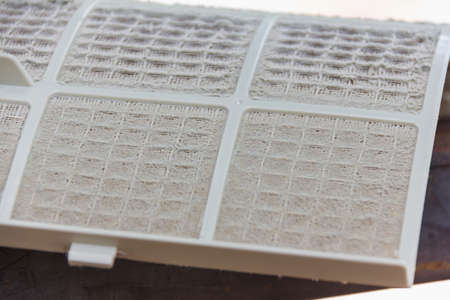 close up on air conditioner filter is very dirty after remove from unit wait clean put on floor