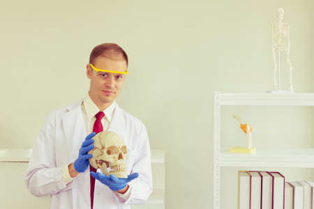 Male scientist wearing blue safety glasses and hold skull isolated with white backgroundの写真素材