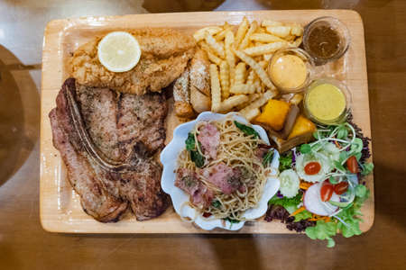 Pork steak with fries and vegetables on the food tray in restaurant, top view styleの写真素材