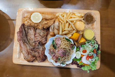 Pork steak with fries and vegetables on the food tray in restaurant, top view styleの写真素材