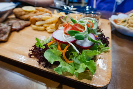 Pork steak with fries and vegetables on the food tray in restaurantの写真素材