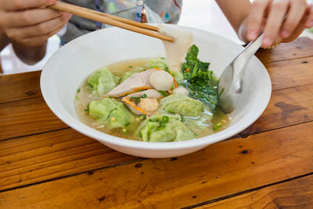 Pork dumplings with green tapioca flour and red pork slice and vegetable in white bowl by chopsticks...