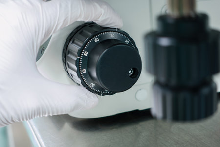 hand wear white glove turn scale adjusting focus of microscope at working room