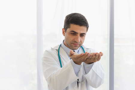 male doctor held his hands close to each other and looked at the hand that analyzed something in the hospital roomの写真素材