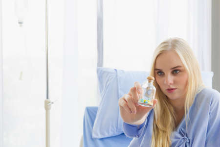 focus pill bottle was female patient holding and show while setting on bed in hospitalの写真素材