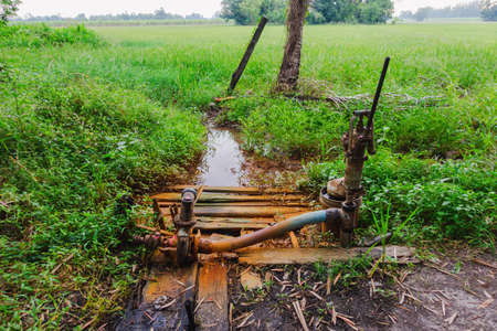 old water pump was used to pump water from under the ground to the rice fields at dayの写真素材