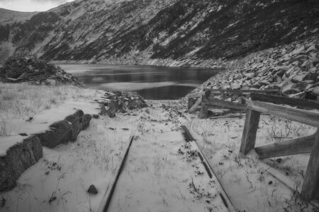 A disused rail track covered in snow at the bank of Norwegian fjord. During warmer months it is now used to launch boats in the fjord.の写真素材