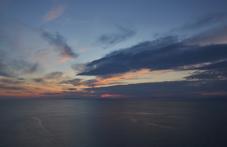 Sky glowing orange and dark blue clouds over the sea in North Wales just after sunset.の写真素材