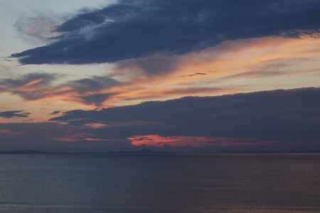 Sky glowing orange and dark blue clouds over the sea in North Wales just after sunset.の写真素材