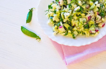 salad with radishes, cucumber greens and green onion sauce served on the side cucumbers and green peasの写真素材