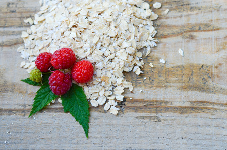 Oatmeal with a pile of fresh raspberries on a wooden Board