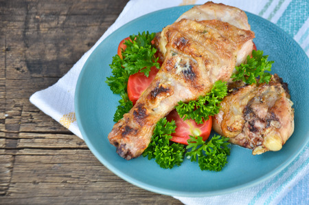 fried chicken plate with greens and tomatoes on wooden backgroundの写真素材