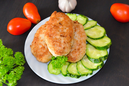 patties of fish next to sliced cucumbers in a dish and the vegetables next to the blackの写真素材