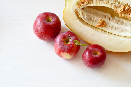 three red apples and pieces of melon on the plate and cut the melon next on white backgroundの写真素材