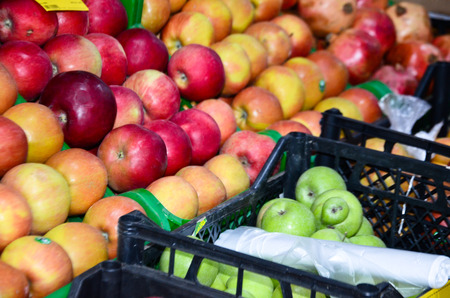 in plastic boxes with apples in the supermarket next to the packagesの写真素材